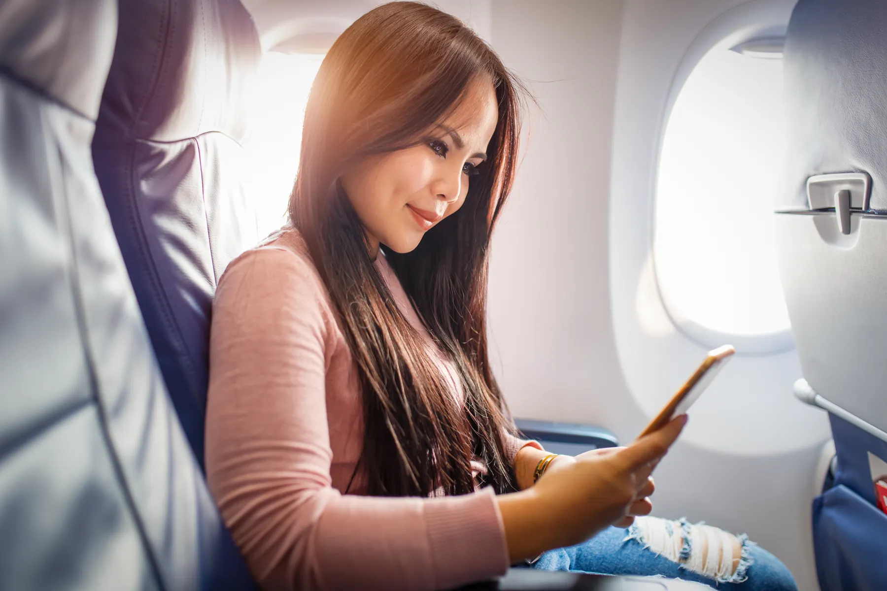 Airline passenger using her smartphone in a window seat