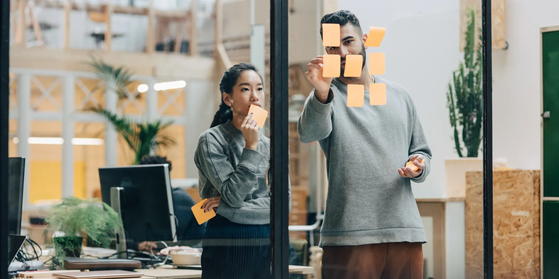 Colleagues planning with sticky notes on a glass wall in an office