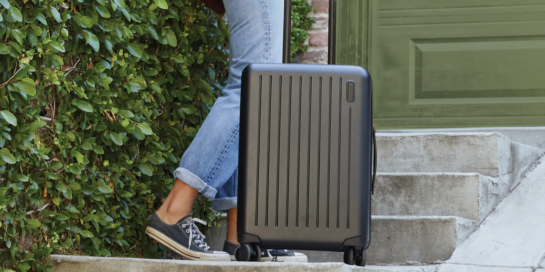 Person leaving home with a hard-shell carry-on suitcase
